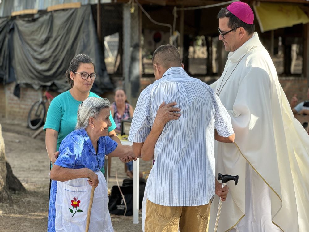 Santos Alfaro Ayala hugs his mother as his aunt and Bishop Oswaldo Escobar Aguilar look on at an April 13 Mass in Guarjila, El Salvador. The Mass celebrated his release after being wrongly detained for three months.