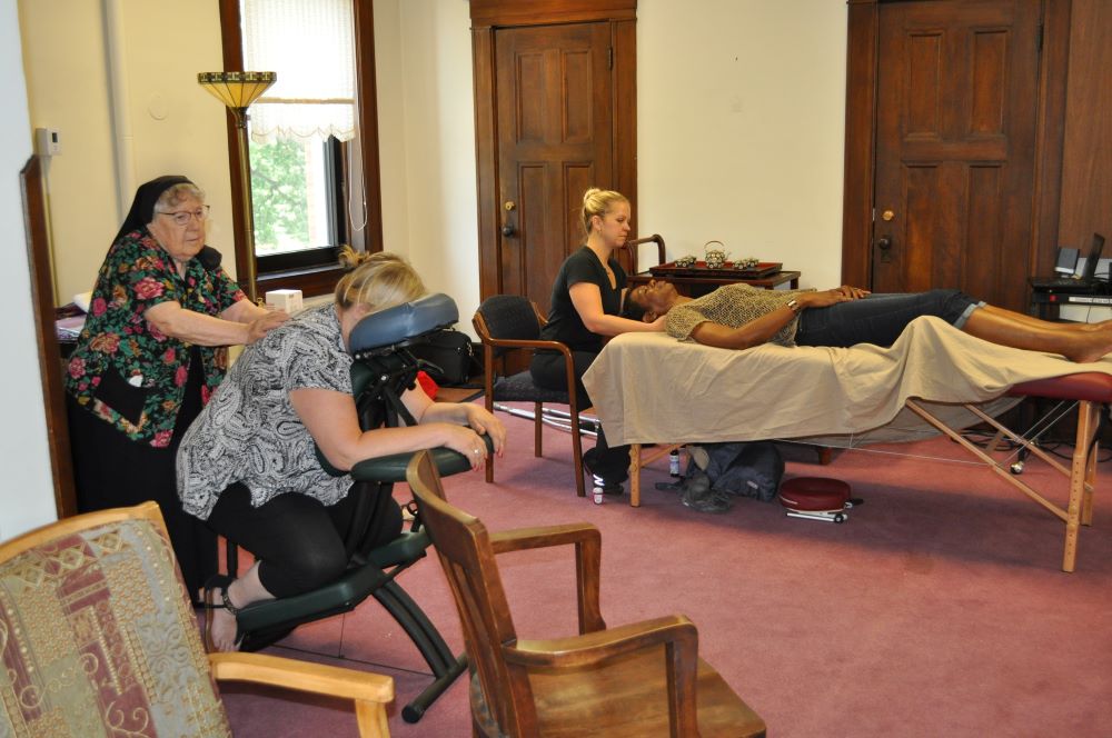 Sr. Rosalind Gefre (left) gives a therapeutic massage in 2017 at one of the massage clinics she started.