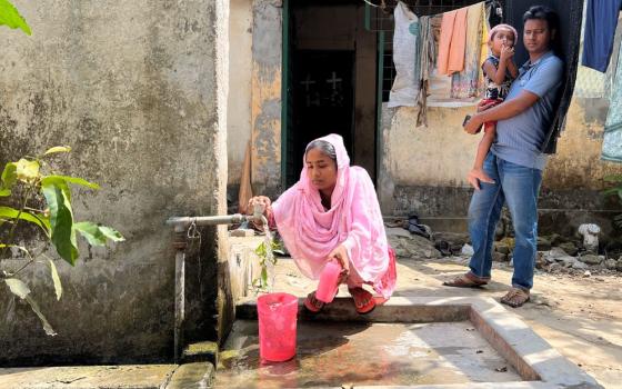 Khadiza Akhter fills up pitchers with water from a spigot in front of her home in Savar, Bangladesh. (Grist/Mahadi Al Hasnat)